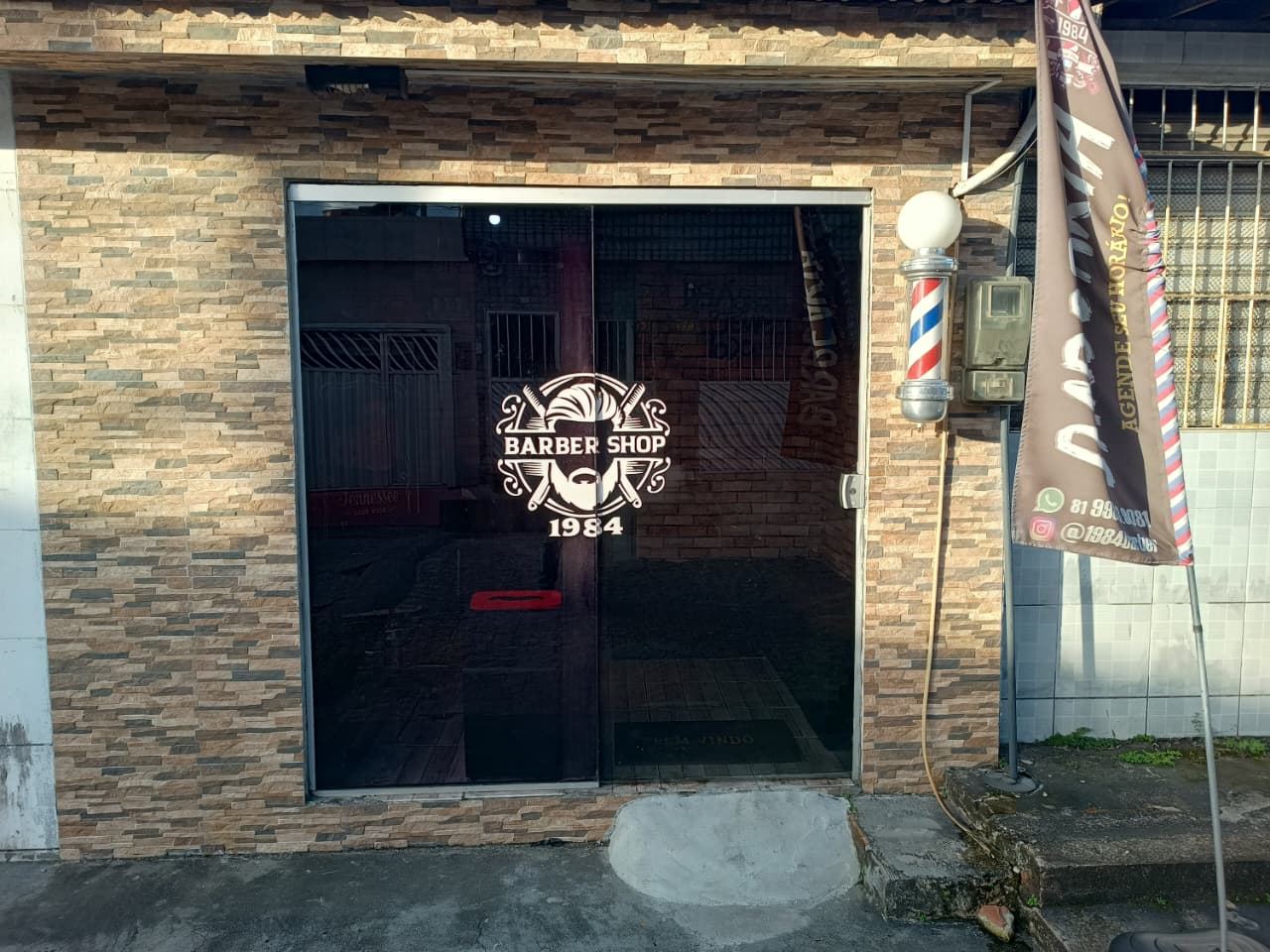 Fachada da 1984 Barbershop com poste de barbeiro na entrada